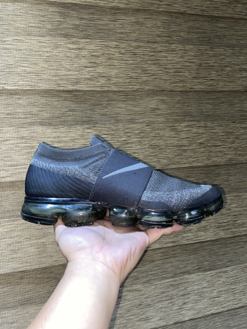 Nike Air Vapormax Moc Strap Grey Sneakers (Category: Casual Shoes) located in Quezon City. Submitted by notmiggol (Listing ID 1470521833, Image 2). Description: Nike Air Vapormax sneakers in dark grey. Slip-on design with a wide midfoot strap and prominent Swoosh branding. Flyknit upper construction for breathable comfort. Signature bubble air sole unit. Visible wear on the outsole bubbles and minor scuffing. Great pickup if you love the Vapormax