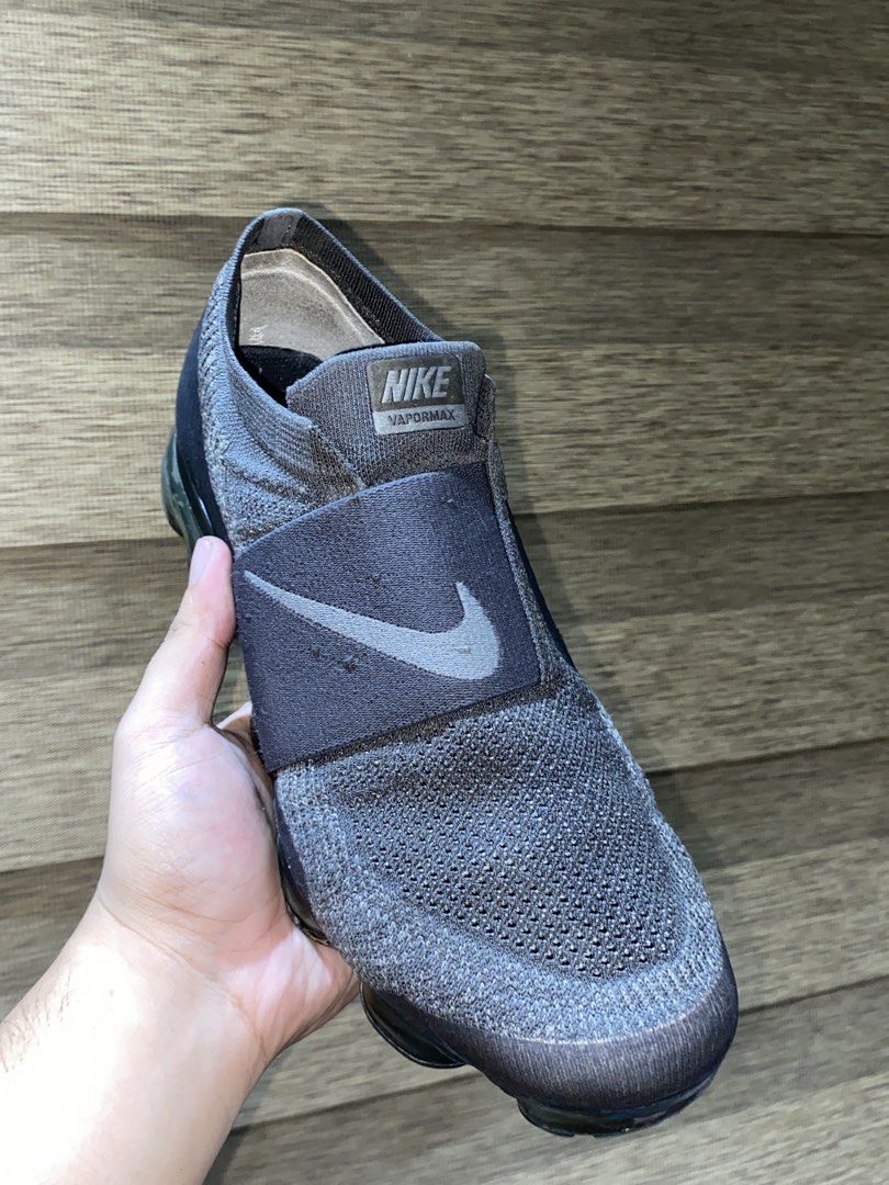 Nike Air Vapormax Moc Strap Grey Sneakers (Category: Casual Shoes) located in Quezon City. Submitted by notmiggol (Listing ID 1470521833, Image 3). Description: Nike Air Vapormax sneakers in dark grey. Slip-on design with a wide midfoot strap and prominent Swoosh branding. Flyknit upper construction for breathable comfort. Signature bubble air sole unit. Visible wear on the outsole bubbles and minor scuffing. Great pickup if you love the Vapormax