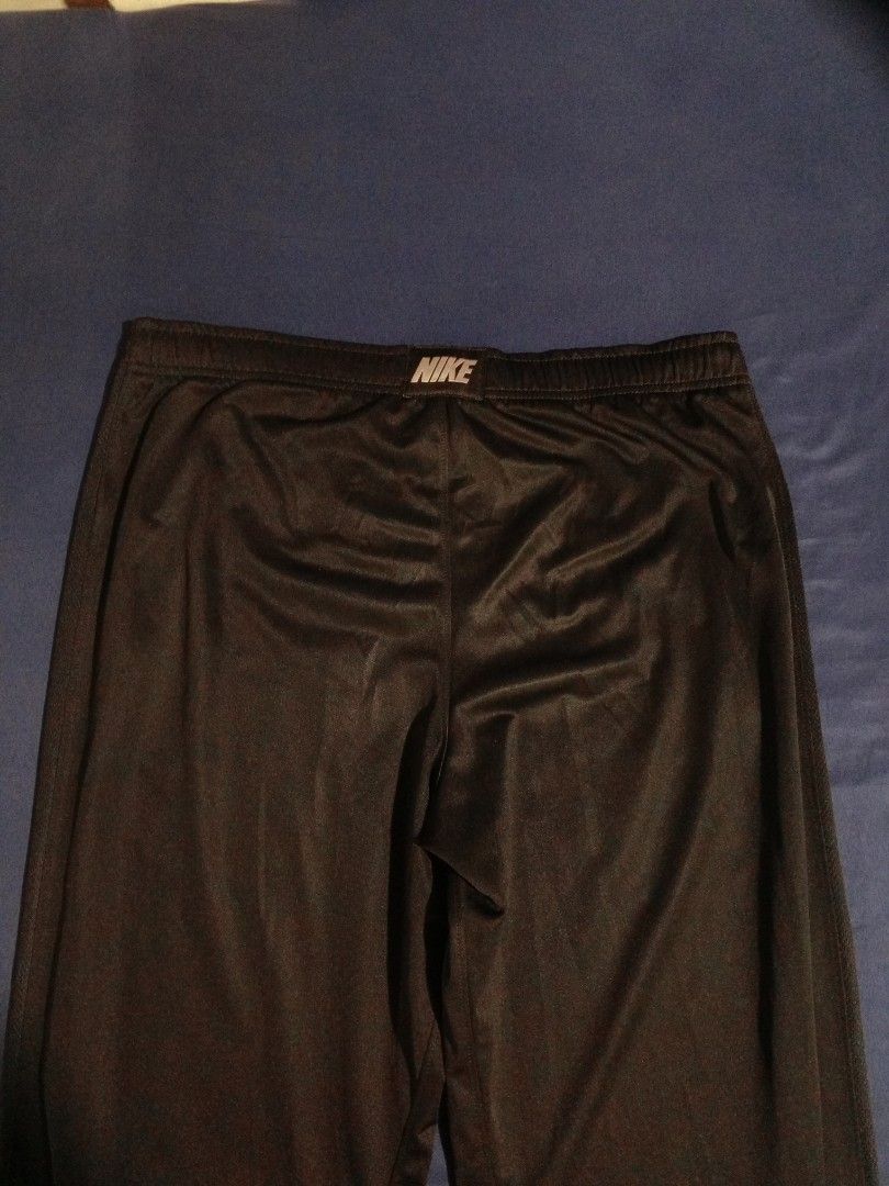 Nike Black Athletic Track Pants with Side Stripes (Category: Joggers) located in Castillejos. Submitted by eross07 (Listing ID 1470473649, Image 2). Description: Black Nike athletic track pants. Grey vertical stripes run down both outer legs. Classic Nike swoosh logo embroidered on the left thigh. Elastic waistband with a drawstring closure inside. Additional Nike branding patch centered on the back waistband. Comfortable synthetic athletic mater
