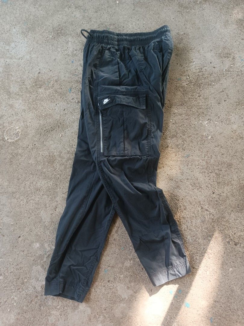 Nike Black Cargo Pants Size S (Category: Joggers) located in Manila. Submitted by anjo1 (Listing ID 1470556850, Image 3). Description: - Brand: Nike - Item: Cargo pants - Color: Black - Size: S - Material: Lightweight nylon (Made in Indonesia) - Waistband: Elastic with adjustable drawstring - Pockets: Multiple utility pockets with zippers - Branding: Classic white Nike patch - Style: Streetwear / Casual - Condition: Clean overall -26-34 x 35.5.