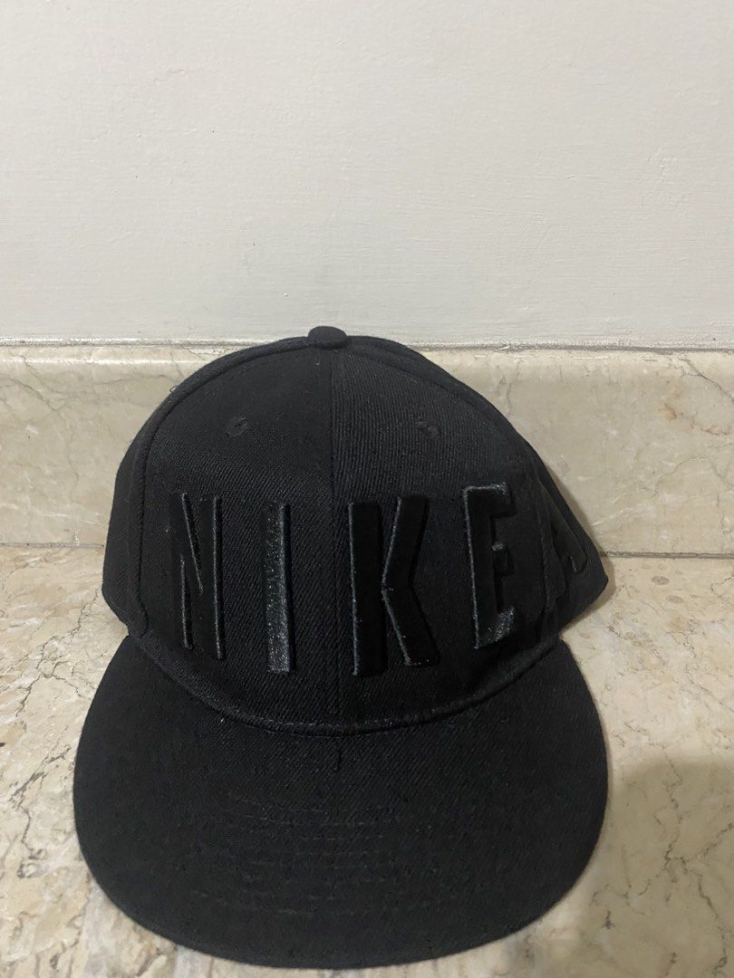 Nike Black Flat Brim Cap with Raised Letters (Category: Caps & Hats) located in Manila. Submitted by primomirp (Listing ID 1470458054, Image 1). Description: - Brand: Nike - Style: Flat brim snapback cap - Color: Black with large raised block letters wrapping around - Details: Interior taped seams with 'Engineered to the exact specifications of championship athletes' - Closure: Adjustable snapback - Condition: Clean inside and out, minimal wear.