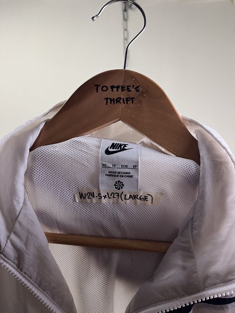 Nike White Windbreaker Jacket Oversized Swoosh (Category: Coats, Jackets and Outerwear) located in Malaybalay. Submitted by toffee_s_thrift0.1 (Listing ID 1470517663, Image 3). Description: - Brand: Nike - Style: Windbreaker with large black swoosh on front, full zip closure, and side pockets - Color: White with black branding - Size: Tagged XS, but fits like a Large (Actual measurements: Width 24.5" x Length 27") - Materials: 100% nylon body, 10