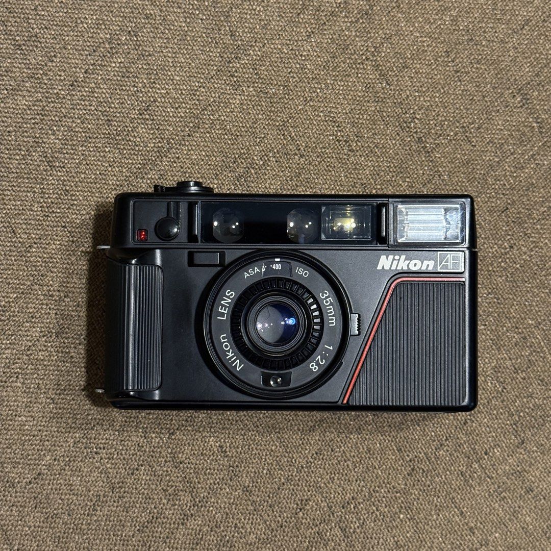 Nikon L35AF 35mm Film Camera (Pikaichi) (Category: Cameras) located in Las Pinas. Submitted by rtmrz (Listing ID 1470479213, Image 1). Description: Nikon L35AF 35mm Film Camera (ISO 400) Recently CLA’d and fully working. The battery door is a little loose but still closes properly. It just needs careful handling. Inclusions: * Camera strap * Energizer Original AA/AAA Battery Charger * 4 rechargeable AA batteries (1.2V, 2450mAh) RFS: No longer usi