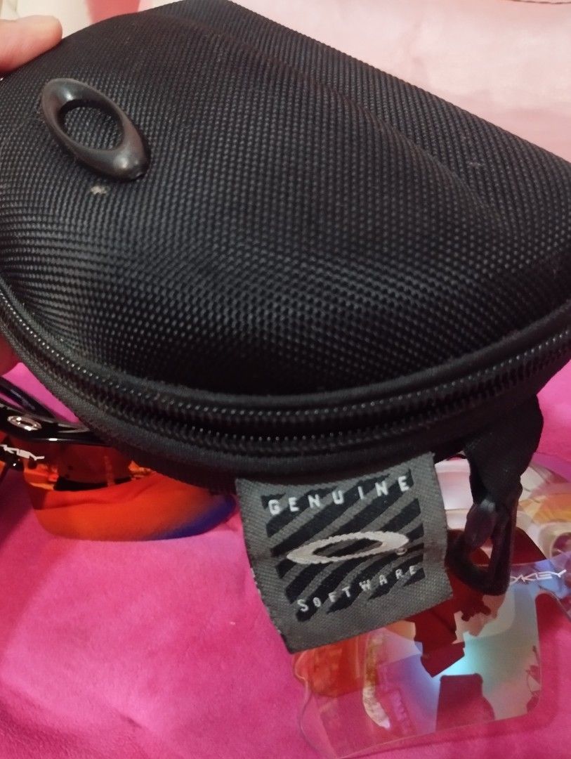 Oakley Hard Shell Sunglasses Case with Genuine Software Tag (Category: Sunglasses & Eyewear) located in Taguig. Submitted by blairescloset (Listing ID 1470474037, Image 3). Description: - Authentic black hard shell case for Oakley sunglasses - Durable textured fabric exterior with the iconic Oakley oval logo - Features the signature grey 'Genuine Software' woven fabric label - Smooth and reliable zipper closure - Sturdy built to protect your shad