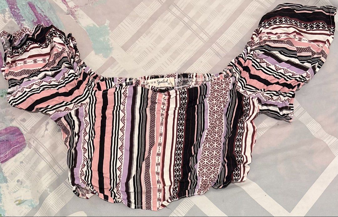 Off-Shoulder Crop Top Striped XS (Category: Blouses) located in Manila. Submitted by areiei (Listing ID 1470366092, Image 2). Description: - Brand: Live to be Spoiled - Size: XS - Color/Pattern: Pink, black, purple, and white vertical stripes - Style: Off-shoulder crop top with short ruffled sleeves and elastic neckline - Fabric: Lightweight and breathable for warm weather - Versatility: Pairs easily with high-waisted shorts or jeans - Condition: