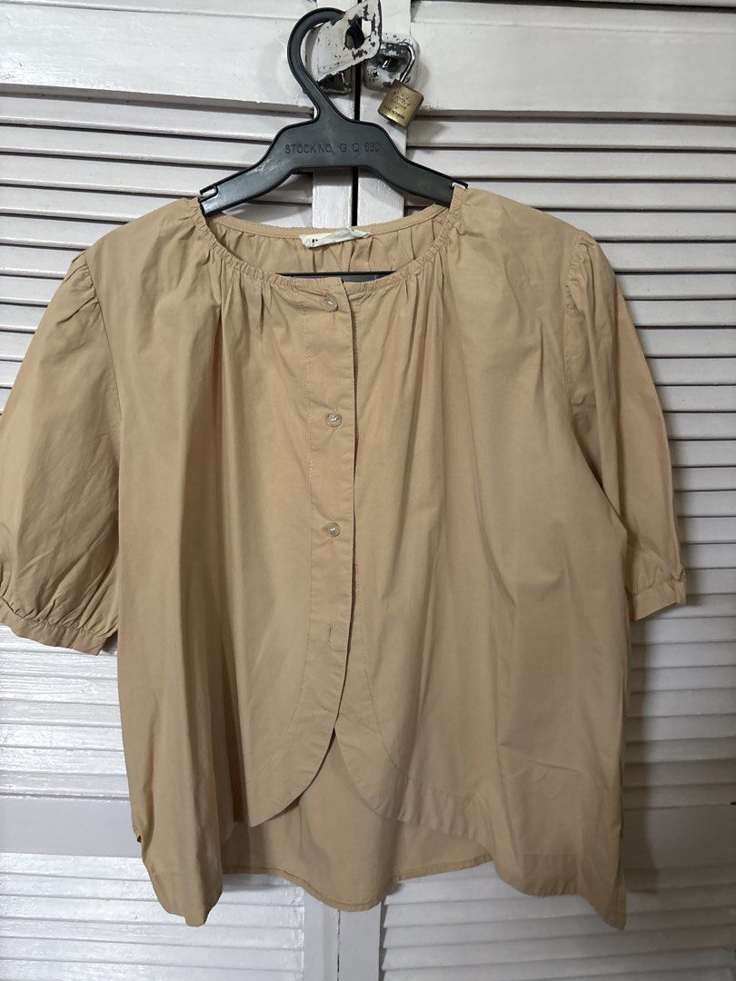 O'gam Beige Button-Up Short Sleeve Blouse (Category: Blouses) located in Makati City. Submitted by goodfindsonly (Listing ID 1470415169, Image 1). Description: - Brand: O'gam - size XL. W-25 L 24.5 - Color: Neutral beige (goes with everything) - Fit: Relaxed fit with short sleeves - Details: Button-up front, gathered neckline, curved front and back hem - Fabric: Lightweight, cotton-like material for all-day comfort.
