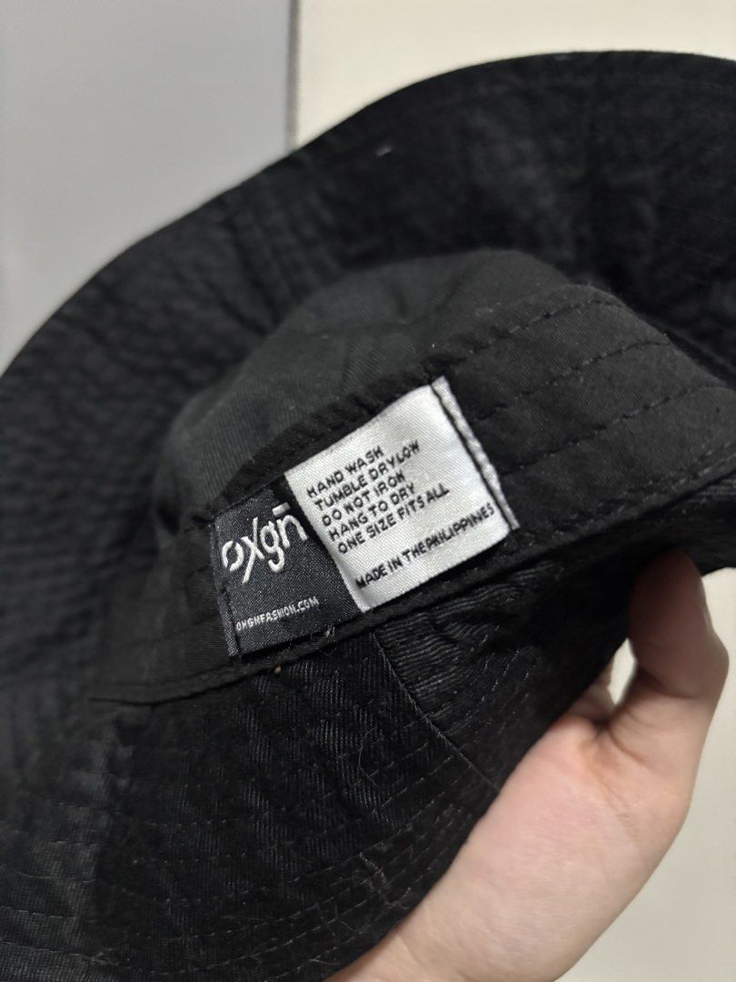 OXGN Black Bucket Hat One Size (Category: Caps & Hats) located in Manila. Submitted by aysshxx (Listing ID 1470475877, Image 3). Description: - Brand: OXGN - Color: Solid black with a grey front logo patch - Size: One size fits all - Material: Clean and well-maintained basic streetwear accessory - Origin: Made in the Philippines - Care Instructions: Hand wash only, tumble dry low, hang to dry, do not iron.