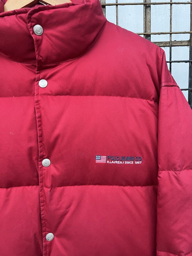 Polo Jeans Co. Ralph Lauren Red Puffer Jacket (Category: Coats, Jackets and Outerwear) located in Manila. Submitted by tomdenzell38299 (Listing ID 1470534830, Image 2). Description: - Brand: Polo Jeans Co. Ralph Lauren - Color: Bright red - Design: Embroidered US flag logo on the chest - Warmth: Thick quilted padding for heavy cold-weather protection - Collar: High stand-up collar with snap buttons over front zip - Pockets: Two lower front patch 