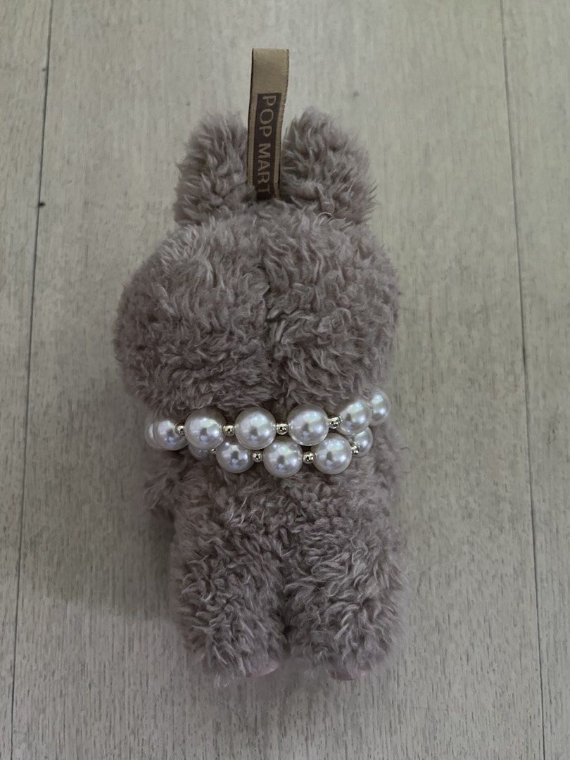 Pop Mart The Monsters Labubu Plush Doll Pendant (Category: Plushies & Soft Toys) located in Quezon City. Submitted by Zandee (Listing ID 1470488656, Image 2). Description: Pop Mart Labubu plush pendant from The Monsters series. Covered in greyish-brown fuzzy fur with soft pink ears and feet. Accessorized with a chunky double-strand pearl necklace and a dark metallic heart charm (added by owner to accesorize ) Official Pop Mart tag on top and bran