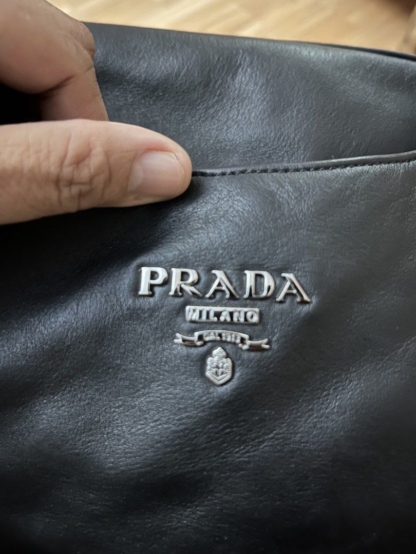 Prada Black Leather Chain Tote Bag (Category: Luxury Bags & Wallets) located in Victorias. Submitted by lan1877 (Listing ID 1470476161, Image 3). Description: - Brand: Prada - Color: Classic Black - Material: Soft, high-quality leather - Hardware: Silver-tone chain straps - Closure: Magnetic main closure with internal zip compartments - Branding: Signature Prada Milano logo plaque on front and interior - Style: Structured yet slouchy tote, perfec