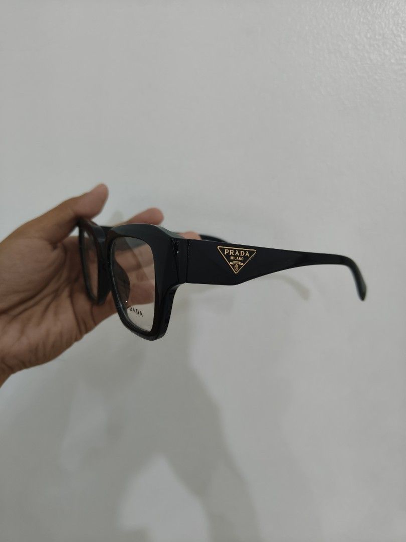 Prada Black Optical Glasses Frame 09Z-F (Category: Sunglasses & Eyewear) located in Davao. Submitted by navil01 (Listing ID 1470403845, Image 2). Description: - Brand: Prada - Color: Glossy black with gold hardware - Model & Size: 09Z-F, 52-16-149 - Features: Iconic gold triangular logo on both temples, chunky statement browline - Origin: Made in Italy - Lenses: Clear demonstration lenses with Prada branding (ready for your custom prescription) -