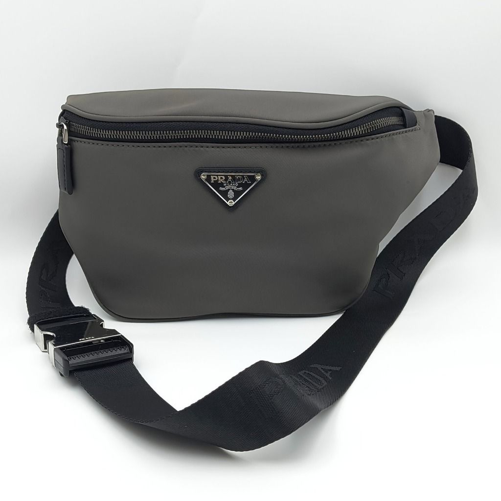 Prada Re Nylon Belt Bag Grey (Category: Luxury Bags & Wallets) located in Cebu City. Submitted by affordabagss (Listing ID 1470522461, Image 1). Description: Prada Re-Nylon Belt Bag crafted in grey Re-Nylon with Saffiano leather trim. Accented with silver-tone hardware, the signature Prada triangle logo, and an adjustable black jacquard strap featuring Prada lettering. The zippered main compartment is lined in Prada-branded fabric and features an