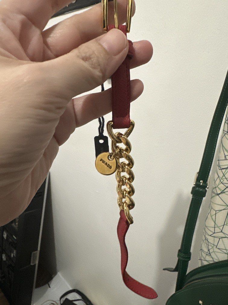 Prada Saffiano Leather Chain Charm Bracelet (Category: Bracelets) located in Malabon City. Submitted by seseche (Listing ID 1470526286, Image 1). Description: Prada Saffiano Leather Chain Charm Bracelet (Model: 1IB263). It is characterized by its red or peony pink crosshatch Saffiano leather strap, a gold-finished chain section, an adjustable buckle closure, and a dangling round charm featuring the engraved Prada logo..