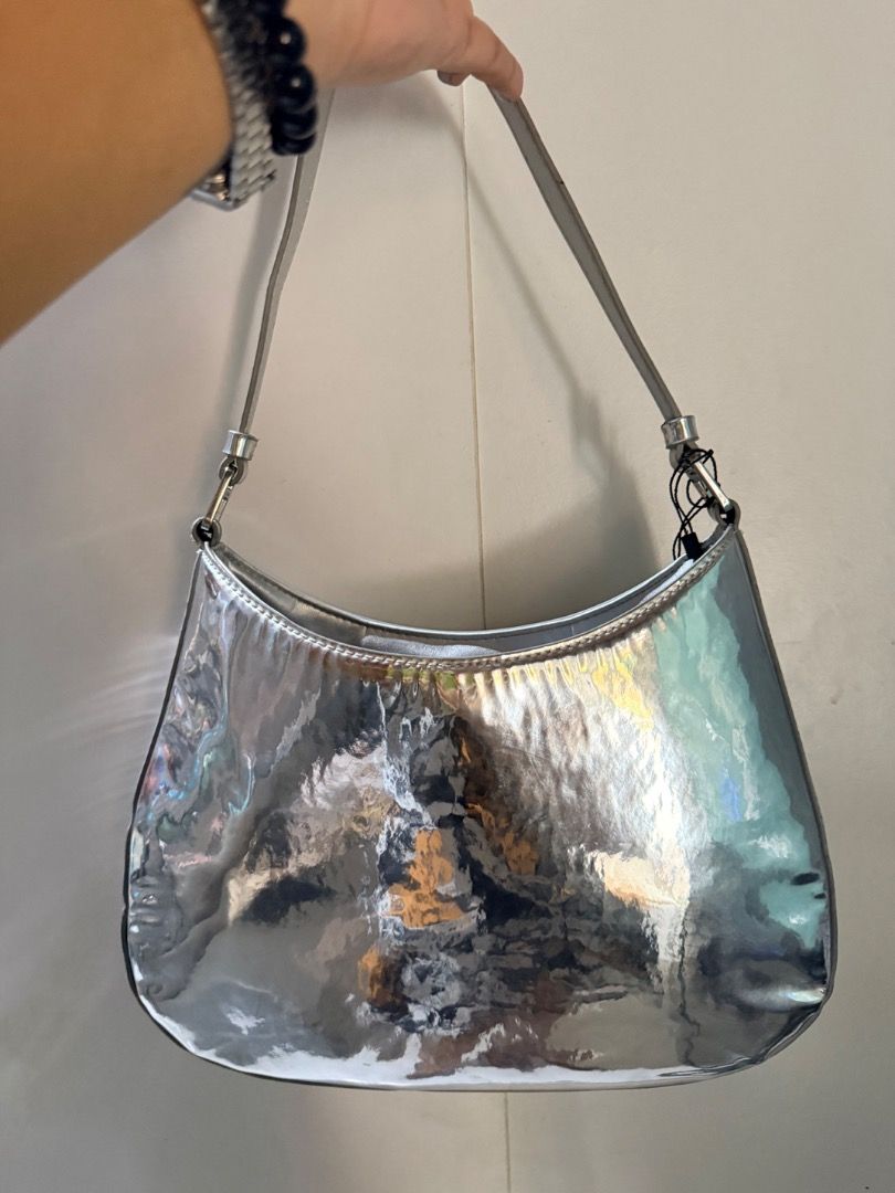 Prada Silver Metallic Shoulder Bag (Category: Luxury Bags & Wallets) located in Manila. Submitted by _outofthecloset. (Listing ID 1470394952, Image 2). Description: - Brand: Prada - Style: Curved hobo shoulder bag with single strap - Color: Metallic silver - Hardware/Logo: Front enamel triangular logo plaque & Prada Milano metal tag - Closure: Magnetic top closure - Interior: Black signature fabric lining with extra slip pocket - Condition: Clean