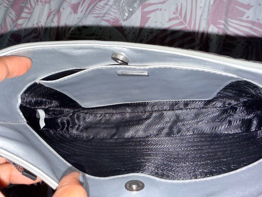 Prada Silver Metallic Shoulder Bag (Category: Luxury Bags & Wallets) located in Manila. Submitted by _outofthecloset. (Listing ID 1470394952, Image 3). Description: - Brand: Prada - Style: Curved hobo shoulder bag with single strap - Color: Metallic silver - Hardware/Logo: Front enamel triangular logo plaque & Prada Milano metal tag - Closure: Magnetic top closure - Interior: Black signature fabric lining with extra slip pocket - Condition: Clean