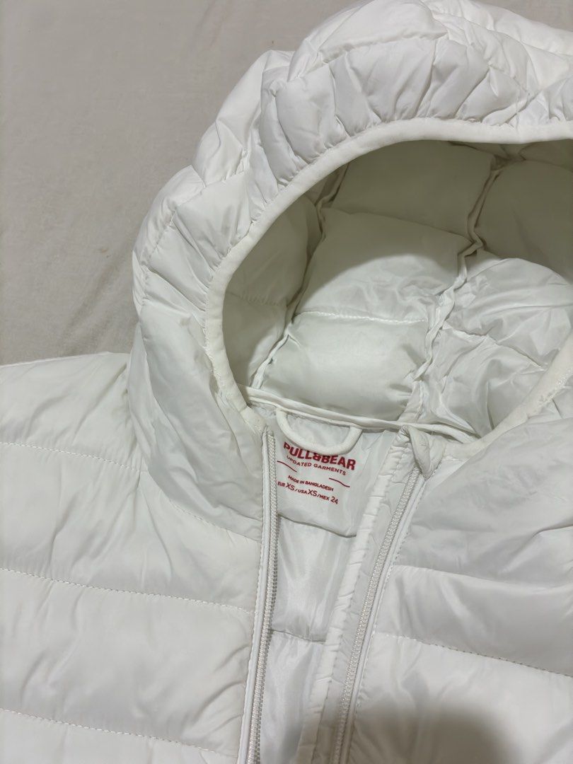 Pull&Bear White Puffer Jacket with Hood XS (Category: Coats, Jackets and Outerwear) located in Mandaluyong City. Submitted by littlecatstore (Listing ID 1470370790, Image 2). Description: - Brand: Pull&Bear - Style: White hooded puffer jacket - Size: XS (fits true to size) - Features: Zip-up front, quilted design, adjustable hem drawstrings - Condition: Clean white color, no stains or flaws - Perfect lightweight winter layer for everyday wear.