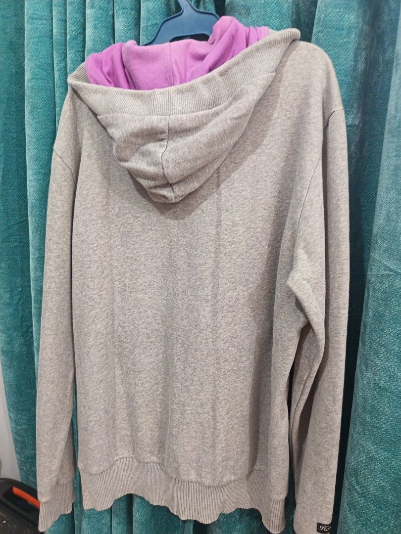 Puma hoodie (Category: Coats, Jackets and Outerwear) located in Cavite. Submitted by vin2za06 (Listing ID 1470384104, Image 3). Description: The image shows a grey PUMA pullover hoodie with a purple and silver brushstroke-style PUMA logo on the front, a V-neck hood lined with purple fabric, and a front kangaroo pocket..