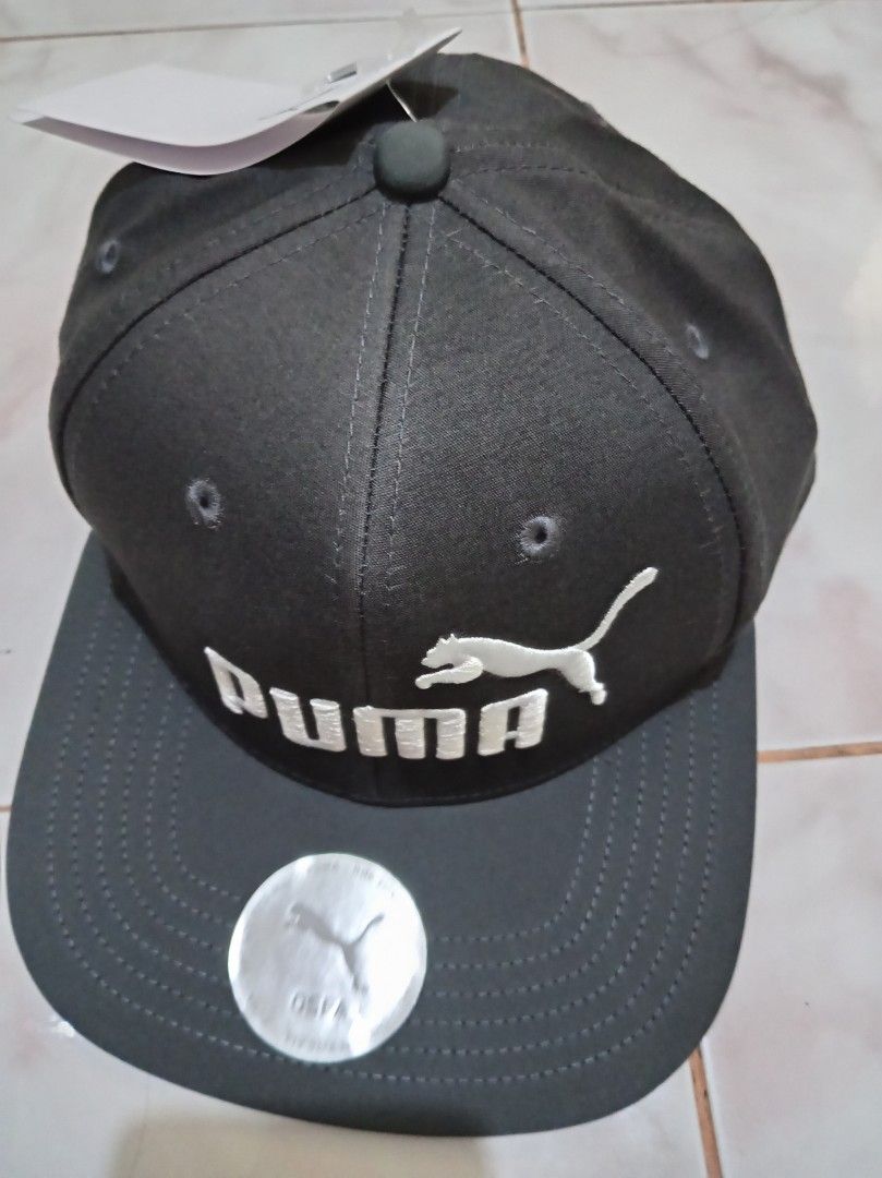 Puma Snapback Cap Dark Grey White Logo (Category: Caps & Hats) located in Las Pinas. Submitted by edpalma09136721 (Listing ID 1470514050, Image 2). Description: - Brand new with original store tags attached - Color: Dark grey with white embroidered Puma logo - Style: Flat brim snapback with holographic sticker - Fit: Adjustable strap at the back for a custom fit.