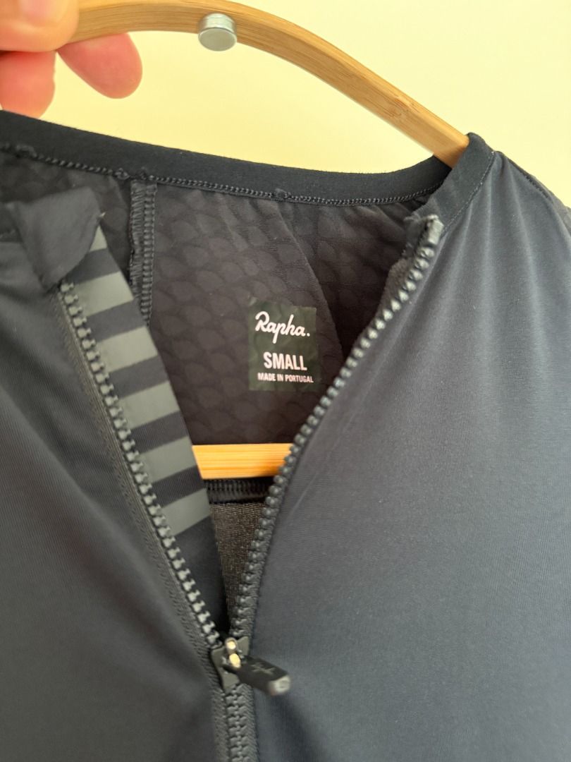 Rapha Cycling Aero Jersey (2) Small Black and Beige (Category: Activewear) located in Las Pinas. Submitted by cali022020 (Listing ID 1470353194, Image 2). Description: - Brand: Rapha - Size: Small - Color: Dark black with bold front lettering - Origin: Made in Portugal - Material: Lightweight technical fabric with textured sleeves and back panels - Features: Zip-up front design 4000 for Two RFS: Decluttering.