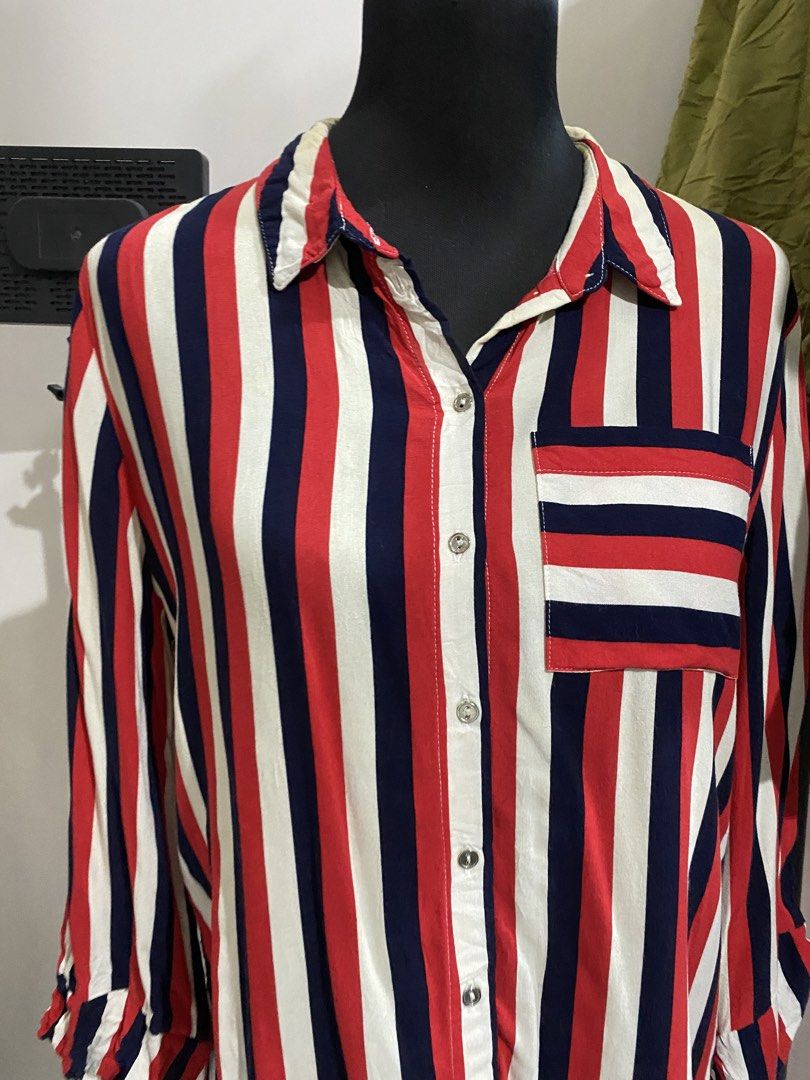 Red, White and Navy Striped Button-Down Shirt (Category: Blouses) located in Manila. Submitted by mpt99876 (Listing ID 1470496460, Image 2). Description: - Bold red, white, and navy blue vertical stripe design - Classic button-down front with a pointed collar - Contrast horizontal stripe chest pocket on the left - Long sleeves with buttoned cuffs - Pleated back detail for extra movement and a relaxed fit - Lightweight, versatile fabric great for 
