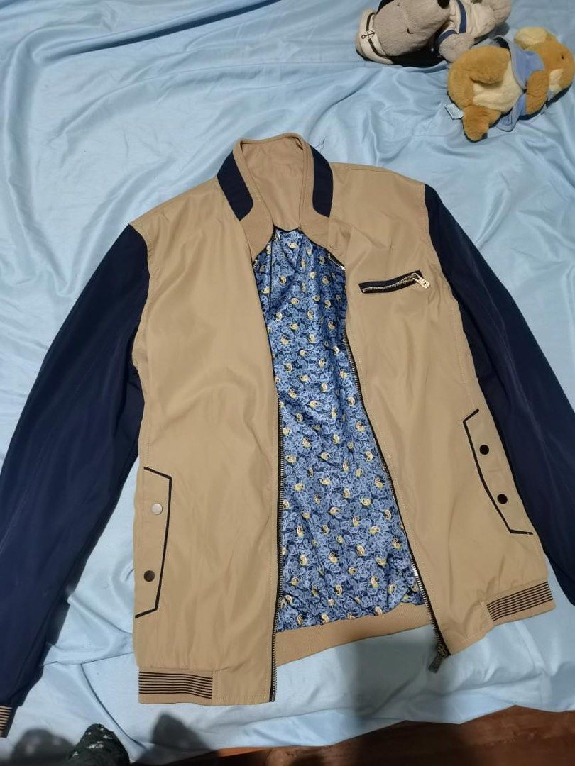 Reversible Bomber Jacket Tan Navy Blue Patterned (Category: Coats, Jackets and Outerwear) located in Manila. Submitted by geminibibo (Listing ID 1470534939, Image 1). Description: Reversible bomber jacket, tan and navy blue panels on one side. Flip it inside out for a blue paisley patterned lining with black sleeves. Zip-up front closure, ribbed cuffs and hem. Functional pockets on the chest and sides. Versatile style, two looks in one jacket..