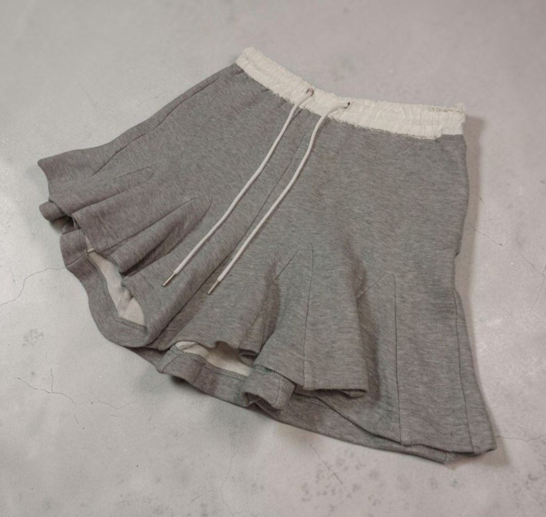 Sacai - Pleated - Sway Sweat - Short (Category: Shorts) located in Manila. Submitted by grmnts_frmthe_slmz (Listing ID 1470393981, Image 3). Description: Sacai sweatshorts in grey with white elasticated waistband. Drawstring closure with metal aglets. Unique flared hem construction giving a skirt-like silhouette. Wstlne 14.5 inches Crtch 11.5 inches Insm 4 inches L 16 inches LgOpng 20 inches Origin: Japan Materials: Cotton 100% Authentic Color Ra