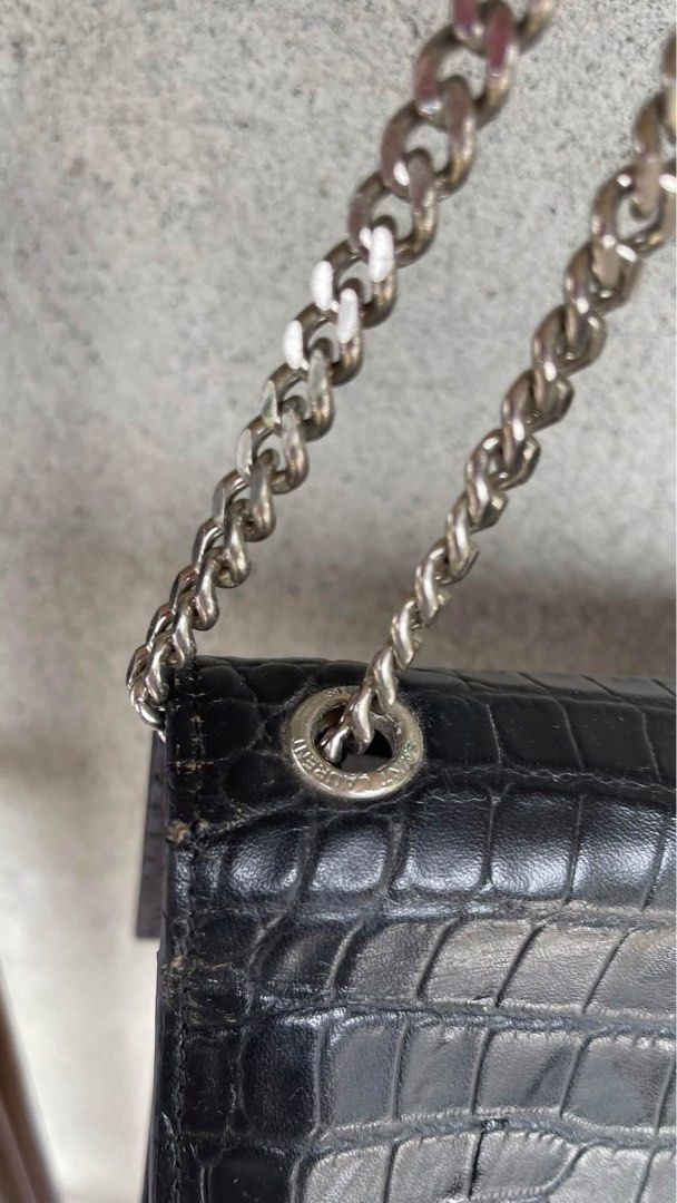 Saint Laurent Black Crocodile Embossed Shoulder Bag (Category: Luxury Bags & Wallets) located in Tabuk. Submitted by collectors_thrift_shop (Listing ID 1470391353, Image 3). Description: - Brand: Saint Laurent - Material: Black crocodile embossed leather - Hardware: Silver-tone with matching chain strap - Closure: Secure magnetic snap - Interior: Features a convenient slip pocket and YSL debossed logo stamp - Condition: Excellent / Well-maintaine