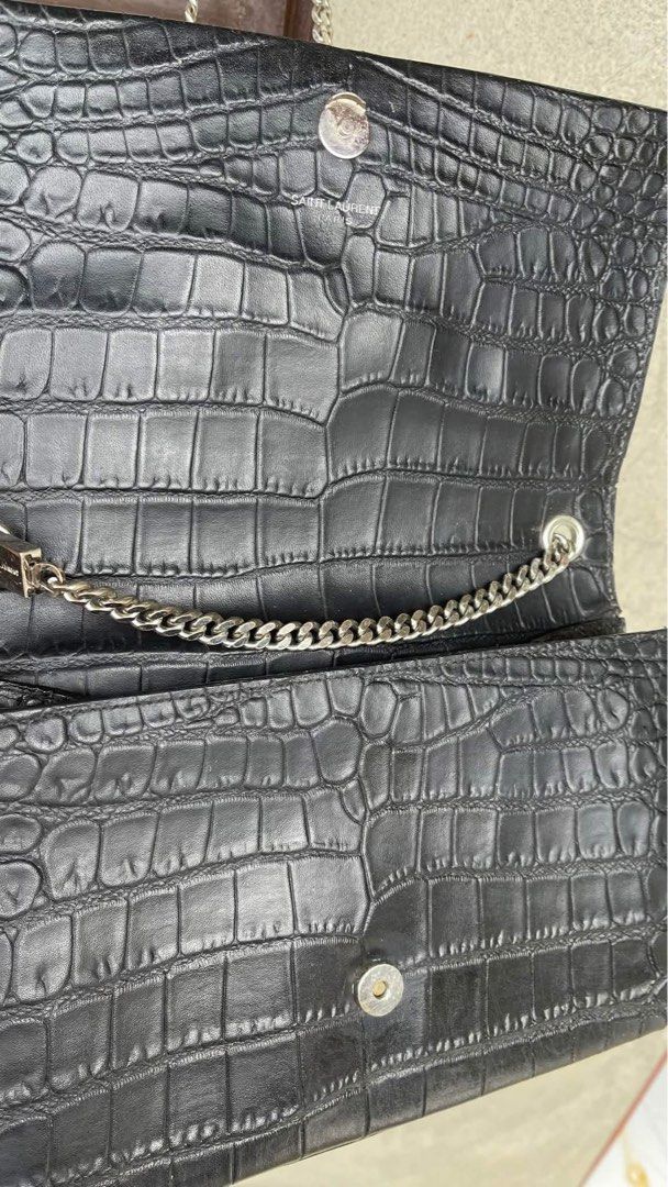 Saint Laurent Black Crocodile Embossed Shoulder Bag (Category: Luxury Bags & Wallets) located in Tabuk. Submitted by collectors_thrift_shop (Listing ID 1470391353, Image 2). Description: - Brand: Saint Laurent - Material: Black crocodile embossed leather - Hardware: Silver-tone with matching chain strap - Closure: Secure magnetic snap - Interior: Features a convenient slip pocket and YSL debossed logo stamp - Condition: Excellent / Well-maintaine
