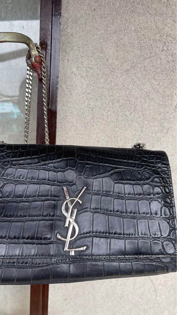 Saint Laurent Black Crocodile Embossed Shoulder Bag (Category: Luxury Bags & Wallets) located in Tabuk. Submitted by collectors_thrift_shop (Listing ID 1470391353, Image 1). Description: - Brand: Saint Laurent - Material: Black crocodile embossed leather - Hardware: Silver-tone with matching chain strap - Closure: Secure magnetic snap - Interior: Features a convenient slip pocket and YSL debossed logo stamp - Condition: Excellent / Well-maintaine
