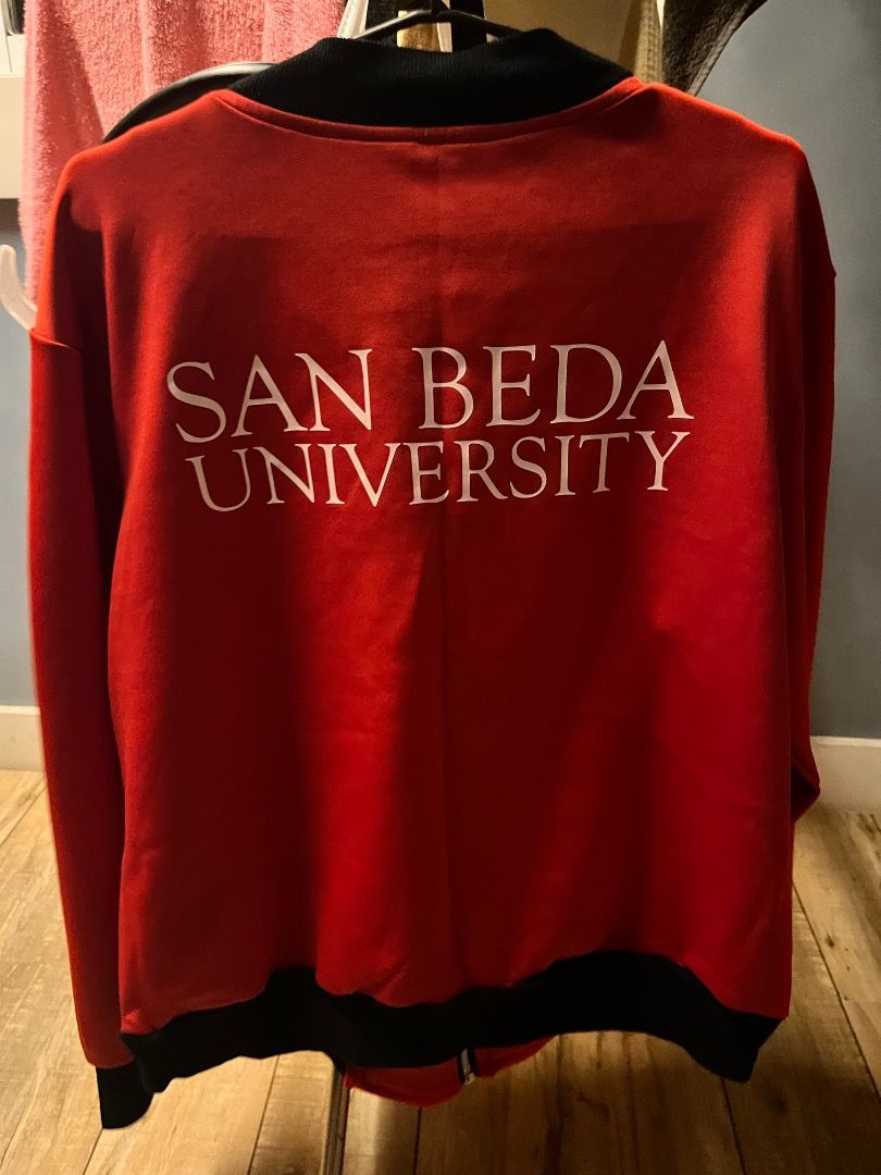 San Beda University Red and Black Bomber Jacket (Category: Coats, Jackets and Outerwear) located in Pasig City. Submitted by vastpenguin.671612 (Listing ID 1470452446, Image 2). Description: - Authentic San Beda University bomber jacket in striking red - Features black ribbed collar, cuffs, and hem for a snug fit - Full front zip closure with a durable silver zipper - University seal printed on the left chest - Bold San Beda University text print