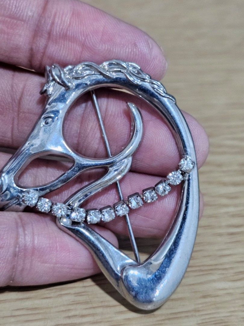 Silver Horse Head Rhinestone Brooch Pin (Category: Brooches) located in Caloocan City. Submitted by smart_shoppers_ville (Listing ID 1470354781, Image 2). Description: - Elegant silver-tone horse head brooch - Sparkling rhinestone accents along the center - Detailed and textured mane design - Reliable standard pin closure on the back - Versatile accessory for jackets, scarves, or bags.