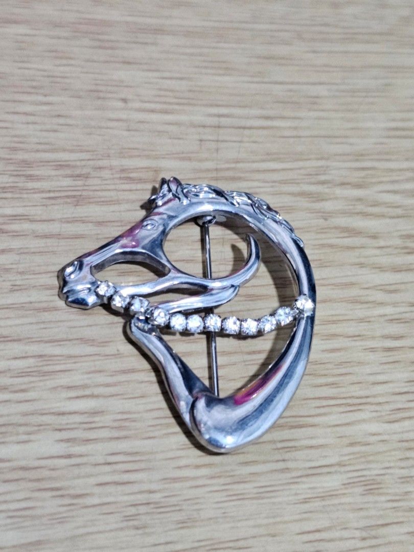 Silver Horse Head Rhinestone Brooch Pin (Category: Brooches) located in Caloocan City. Submitted by smart_shoppers_ville (Listing ID 1470354781, Image 1). Description: - Elegant silver-tone horse head brooch - Sparkling rhinestone accents along the center - Detailed and textured mane design - Reliable standard pin closure on the back - Versatile accessory for jackets, scarves, or bags.