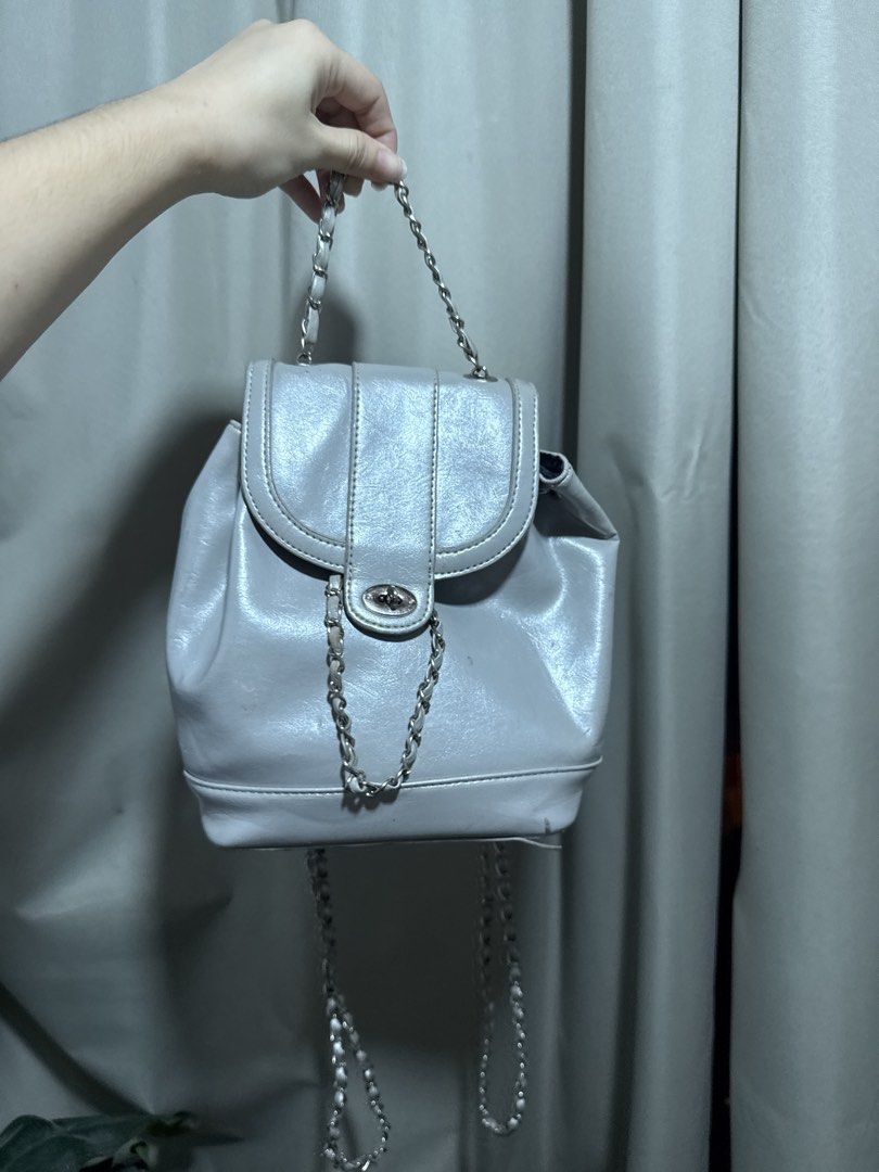 Silver Mini Backpack with Chain Straps (Category: Backpacks) located in Abucay. Submitted by fastlion.584bdf (Listing ID 1470532381, Image 1). Description: - Trendy silver mini backpack with a statement shiny finish - Features stylish silver chain straps and a convenient top handle - Secure front flap closure with a chic twist-lock clasp and drawstring cinch - Compact size ideal for daily essentials while keeping you hands-free - Clean and well-m