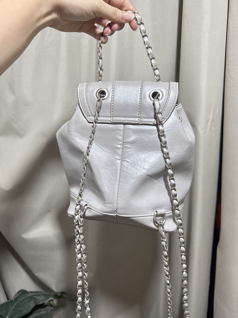Silver Mini Backpack with Chain Straps (Category: Backpacks) located in Abucay. Submitted by fastlion.584bdf (Listing ID 1470532381, Image 3). Description: - Trendy silver mini backpack with a statement shiny finish - Features stylish silver chain straps and a convenient top handle - Secure front flap closure with a chic twist-lock clasp and drawstring cinch - Compact size ideal for daily essentials while keeping you hands-free - Clean and well-m