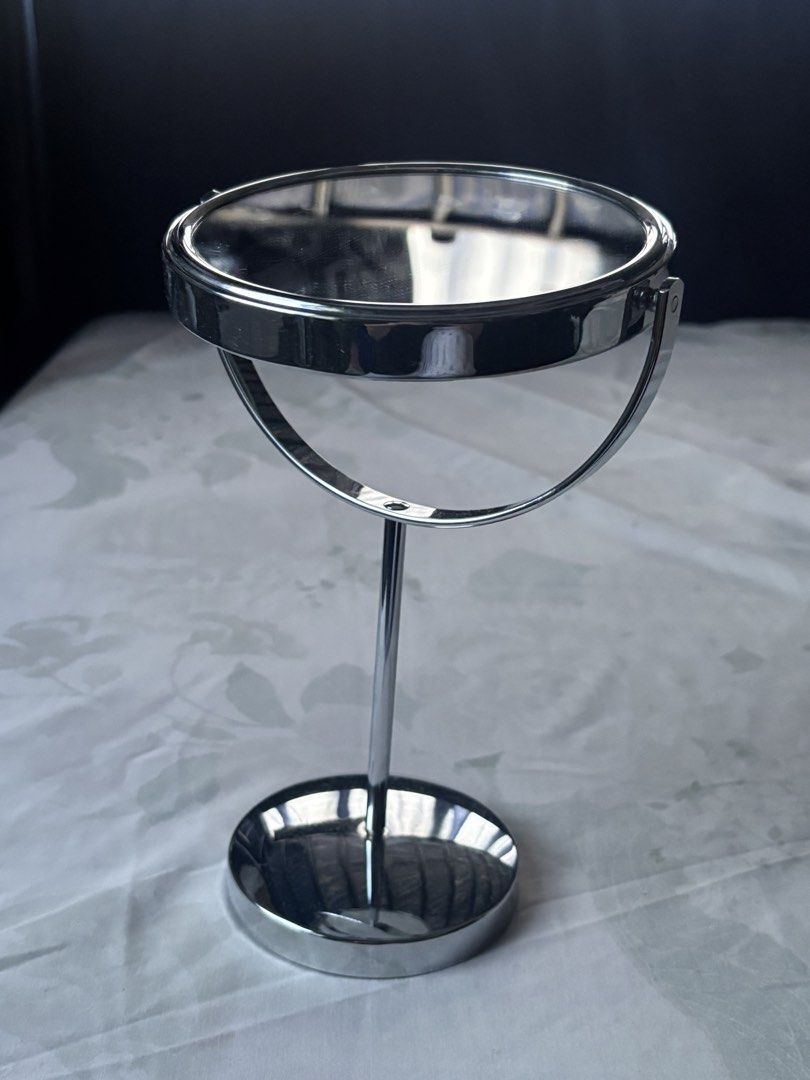 Silver Tabletop Makeup Mirror (Category: Mirrors) located in Makati City. Submitted by dharma444 (Listing ID 1470372638, Image 2). Description: Rfs: Decluttering - Double-sided circular tabletop mirror with full 360-degree rotation - Polished silver finish. Makinis. - Tall stem with a weighted circular base - Has a non-slip at the bottom of the base. MOP: GCash ONLY..