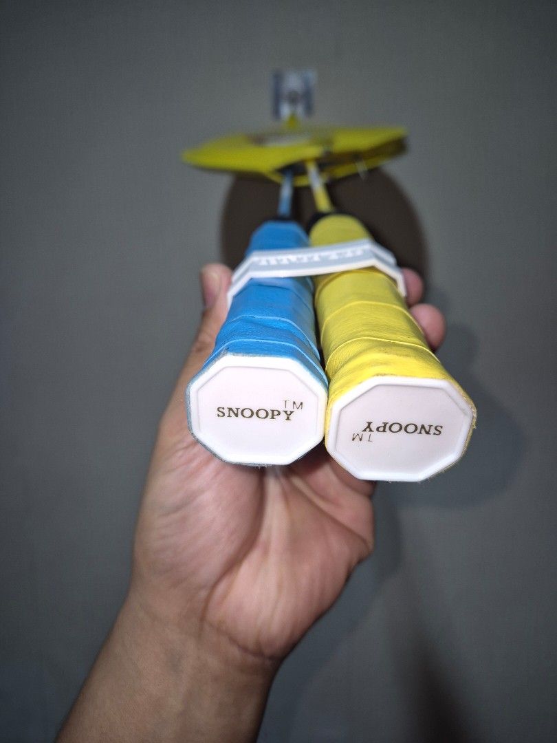 Snoopy Badminton Racket Set with Yellow Storage Bag (Category: Racket and Ball Sports) located in Manila. Submitted by rpaul88 (Listing ID 1470532898, Image 2). Description: - Set of 2 Snoopy badminton rackets (Blue and Yellow) - Includes matching yellow zip carry bag with Snoopy graphics - Wrapped handles with white grip holder clips included - Strings are intact and tight on both frames - Clean condition, perfect for casual park or beach games.