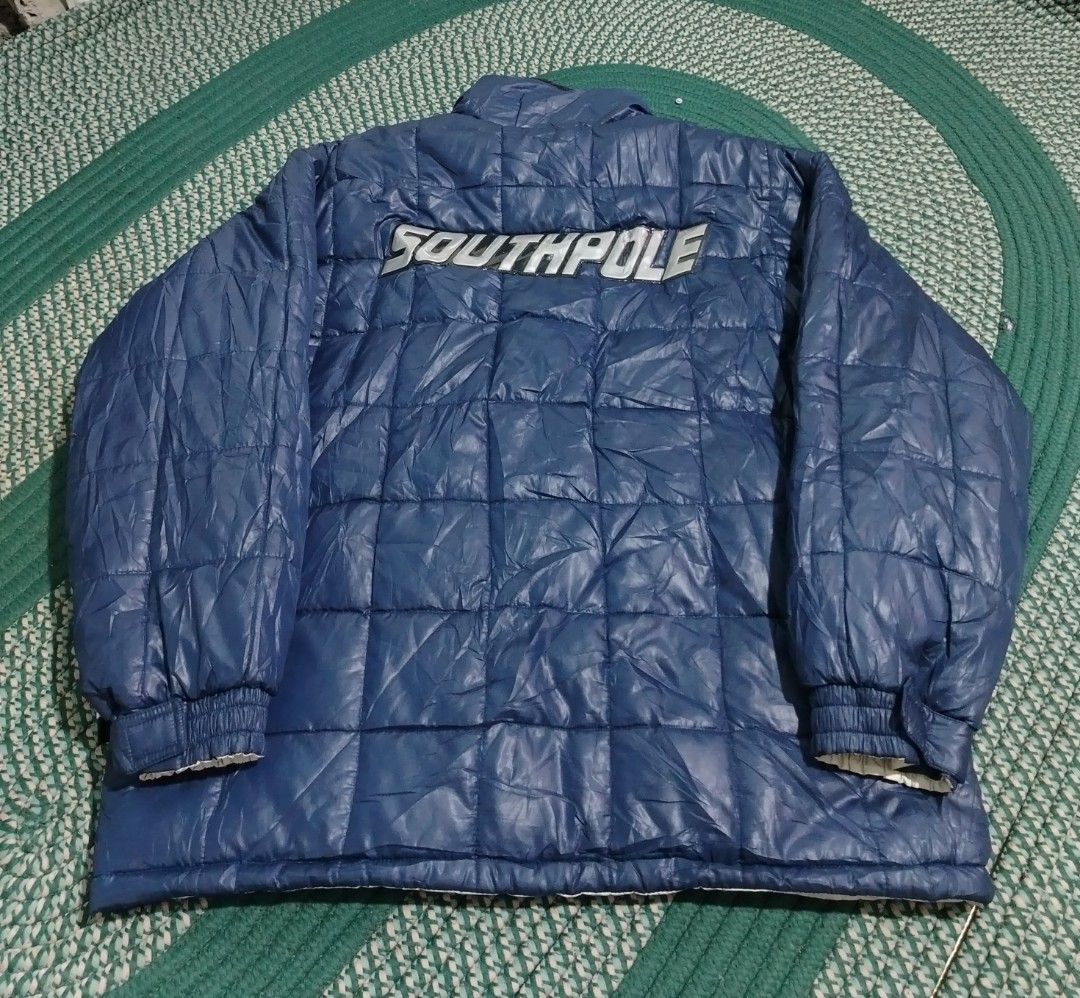 Southpole Reversible Puffer Jacket (Category: Coats, Jackets and Outerwear) located in Lucena. Submitted by thrifteditem (Listing ID 1470357349, Image 3). Description: - Brand: Southpole - Style: Fully reversible puffer jacket - Side 1: Off-white with zip pockets and logo patches - Side 2: Blue quilted nylon with large branding on the back - Details: Chunky front zip with custom pull tab and wind-blocking ribbed cuffs - Condition: Excellent.