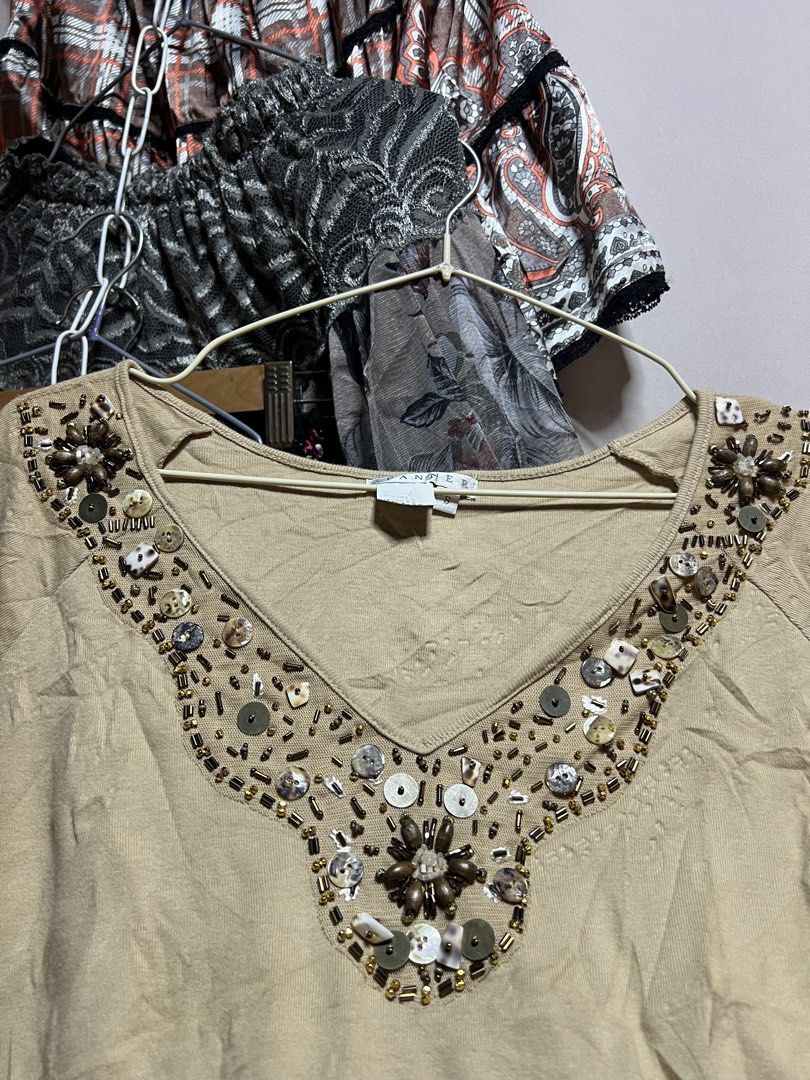 Spanner Beige V-Neck Beaded Top Size S (Category: Blouses) located in Manila. Submitted by threadly (Listing ID 1470399716, Image 2). Description: - Brand: Spanner - Size: Small (Style: S06154) - Color: Beige - Material: Lightweight cotton, relaxed fit - Details: V-neck with wooden beads, sequins, and shell accents - Style: Short sleeves, standard hem, great for casual wear with jeans or skirts.