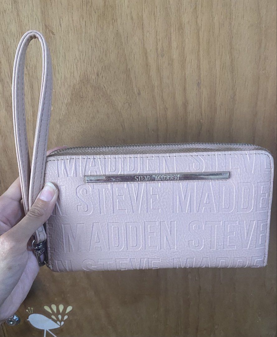 Steve Madden Pink Wristlet Wallet (Category: Wallets & Card holders) located in Bulacan. Submitted by madchen05 (Listing ID 1470357555, Image 1). Description: Steve Madden Pink Wristlet Wallet 🌟Color: Pastel pink with all-over debossed logo 🌟Includes: Matching wrist strap for easy carrying 🌟Interior: Multiple card slots, ID window, and zippered coin compartment 🌟Hardware: Silver-tone with metal logo bar 🌟Flaws: Scratches on metal logo bar & 