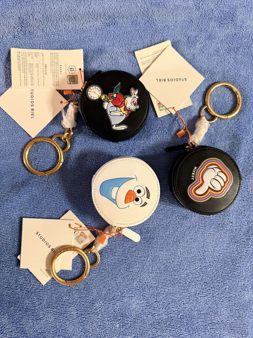 Disney Studios Biel Character Round Pouch Keychain (Category: Character Goods) located in Dasmarinas. Submitted by toyang50 (Listing ID 1470400491, Image 1). Description: - Brand: Three Studios (Biel round pouch keychains) - Available Designs: White Rabbit, Olaf, and Mickey hand graphic - Material: Black and white leatherette with chic gold-tone hardware - Condition: Brand new with original tags and protective plastic on hardware - Features: Secu