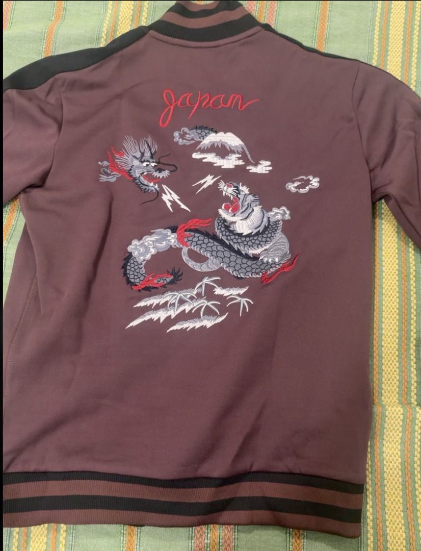 Superdry Vintage Sukajan Jacket (Category: Coats, Jackets and Outerwear) located in Taguig. Submitted by noblephoenix_e3fda3 (Listing ID 1470456462, Image 2). Description: - Color: Brown with contrast dark stripes down the sleeves - Design: Detailed back embroidery featuring a dragon, tiger, mountain scenery, and "Japan" script - Features: Full-zip front, striped ribbed collar, cuffs, and hem - Material: Smooth and sporty fabric, heavyweight - Co