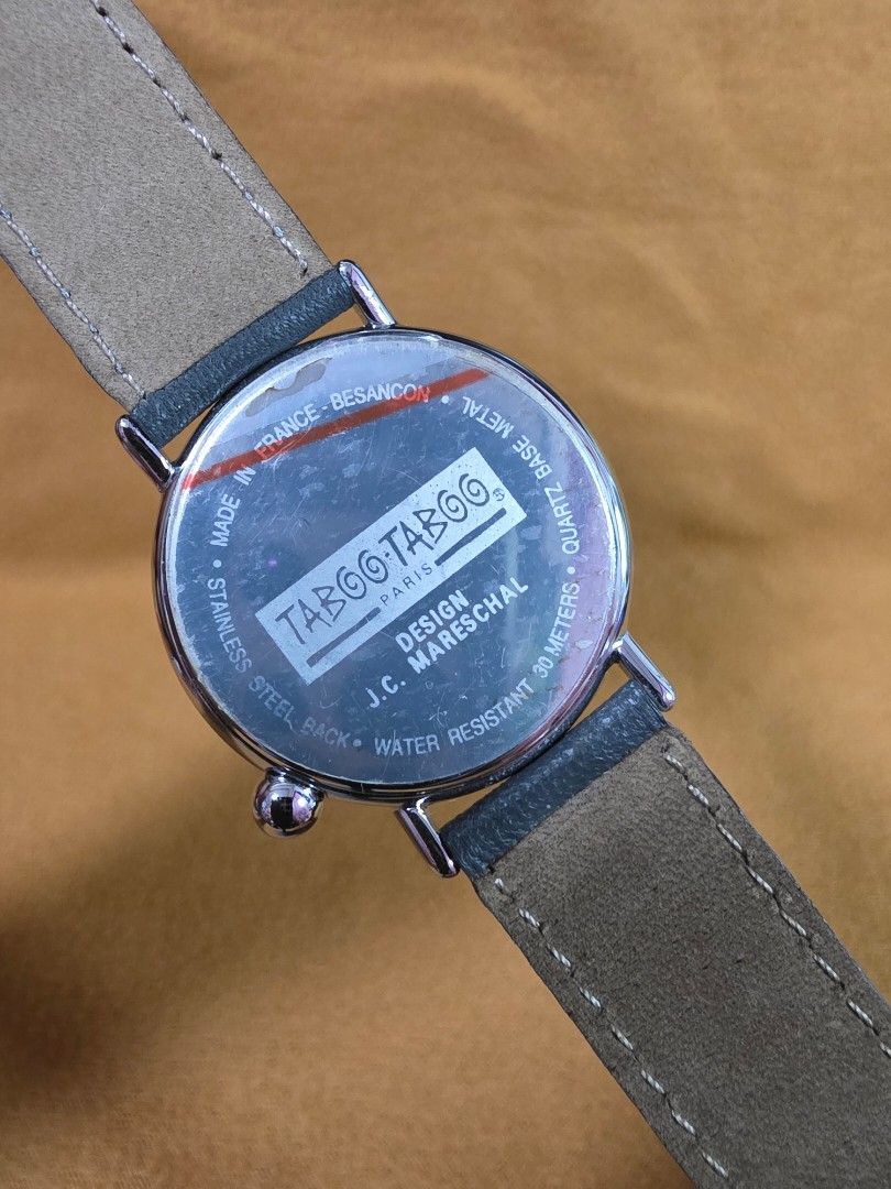 Taboo Taboo Paris J.C. Mareschal Design Quartz Watch (Category: Women's Watches) located in Rosales. Submitted by akumie30 (Listing ID 1470519463, Image 3). Description: Unique Taboo Taboo Paris quartz watch, design by J.C. Mareschal. Silver tone case with white dial featuring a whimsical hunter and duck motif on the hands. Stainless steel back, water resistant 30 meters. Dark grey leather strap with contrast stitching. Made in France. Original T