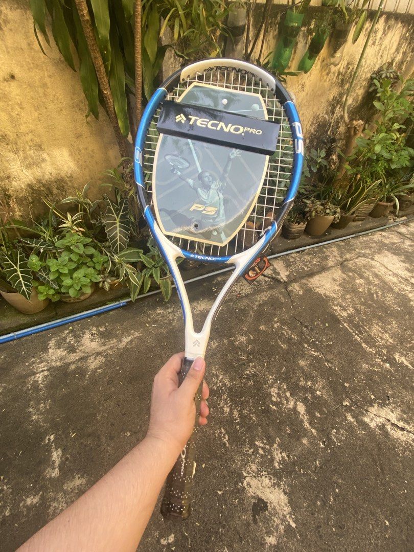 TecnoPro PS6 Tennis Racket (Category: Racket and Ball Sports) located in Quezon City. Submitted by yuval.aguaviva (Listing ID 1470419919, Image 1). Description: - Brand: TecnoPro PS Tennis Racket - Colorway: Stylish blue, white, and black frame - Condition: Brand new with original cardboard head cover and tags still attached - Grip: Standard grip size with a comfortable textured wrap - Strings: Clean, high-quality strings ready for action - Stora