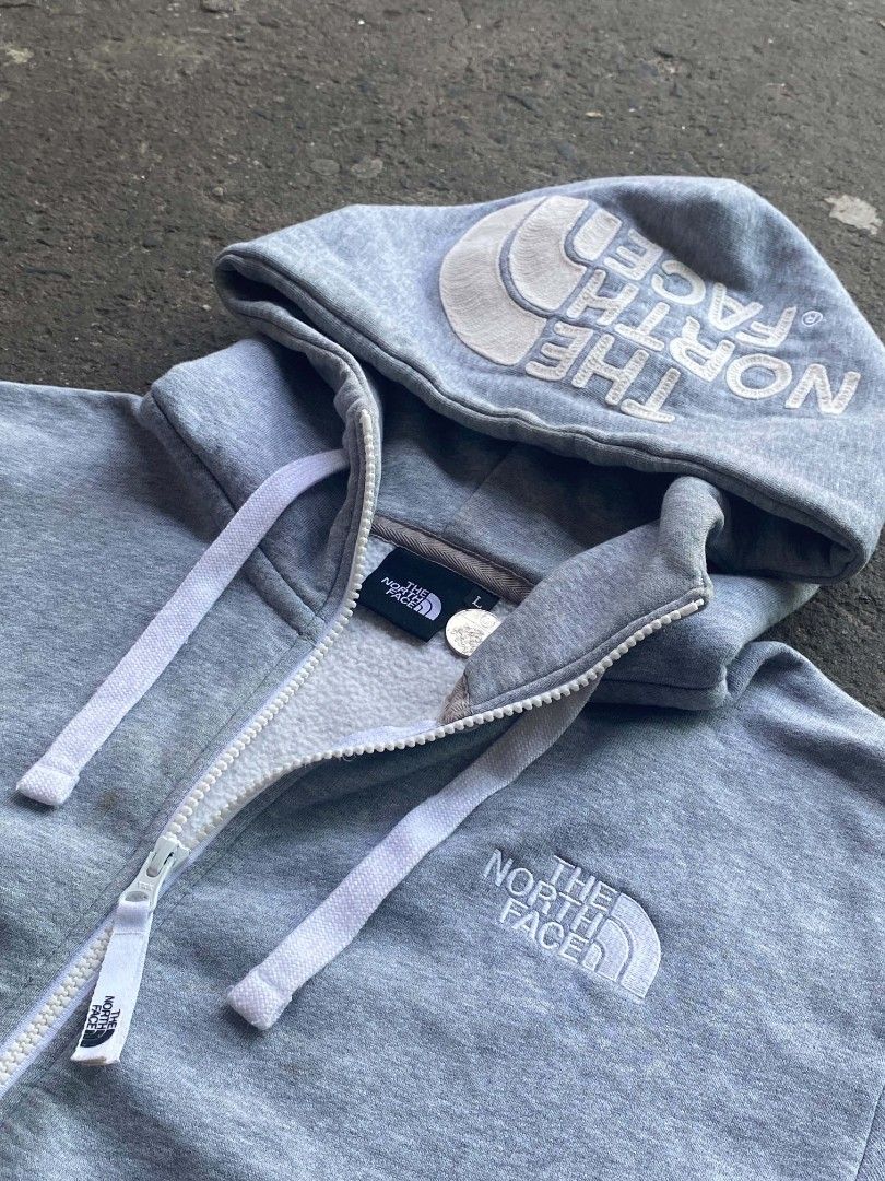 The North Face Grey Full Zip Hoodie (Category: Coats, Jackets and Outerwear) located in Manila. Submitted by raquimsyt (Listing ID 1470357384, Image 2). Description: - Brand: The North Face - Color: Grey - Size: L (tag inside collar) - Full zip closure with branded pull tab - White drawstrings - Large embroidered logo text on the hood - Standard embroidered logo on left chest - Split front kangaroo pocket - Ribbed cuffs and hem - Condition: Excel