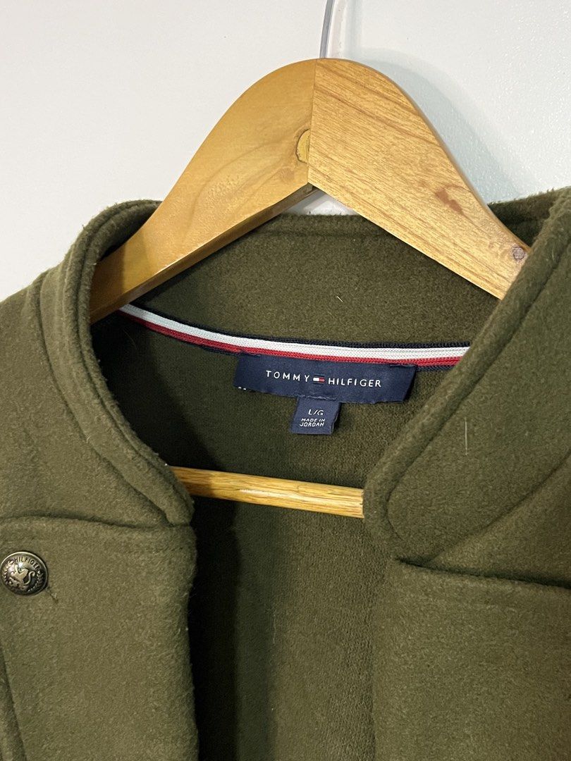Tommy Hilfiger Olive Green Wool Coat Jacket (Category: Coats, Jackets and Outerwear) located in Dasmarinas. Submitted by thriftedbygii (Listing ID 1470532987, Image 3). Description: - Brand: Tommy Hilfiger - Style: Olive green military-style coat with a structured high collar - Closure: Double-breasted brass front buttons - Size: L - Material: Warm wool-like fabric, ideal for cold weather - Care: Dry clean only.