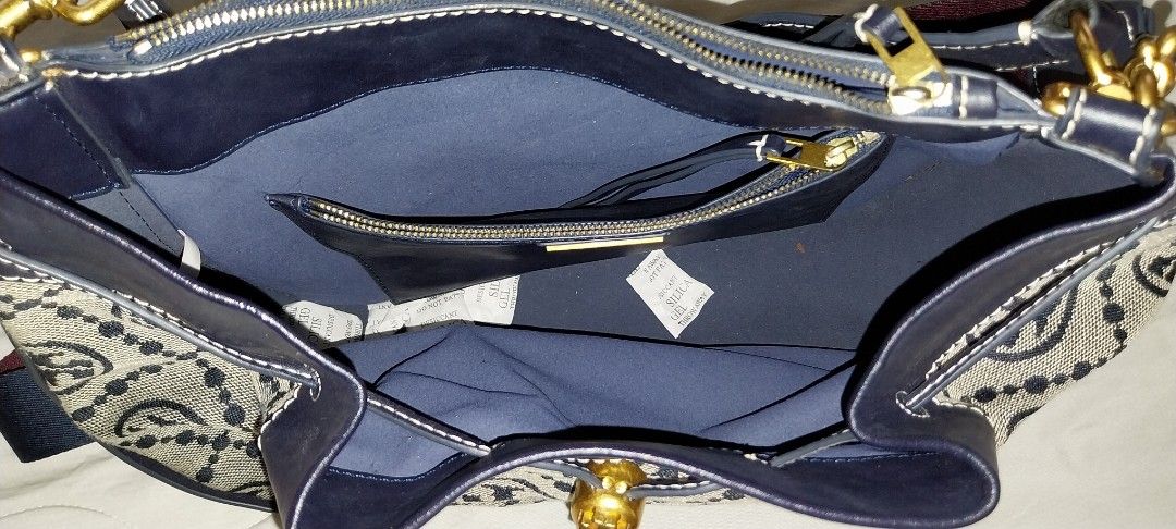 Tory Burch Monogram Jacquard Bucket Bag Navy Blue (Category: Luxury Bags & Wallets) located in Quezon City. Submitted by enryks.boxofstuff (Listing ID 1470375881, Image 2). Description: - Brand: Tory Burch - Style: Bucket Bag - Material: Monogram jacquard fabric with leather trim - Hardware: Gold-tone - Color: Navy Blue - Closure: Drawstring with round logo toggle - Interior: Blue fabric lining with 1 zippered pocket - Straps: Includes top handle