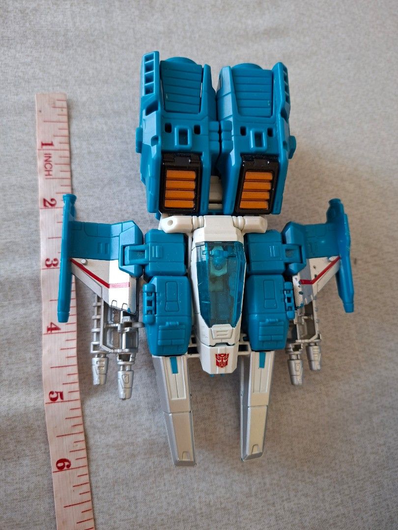 Transformers Tops spin (Category: Vehicle & Diecast Models) located in San Pablo. Submitted by ninojr (Listing ID 1470416246, Image 2). Description: - Item: Transformers Blue & White Jet Toy - Size: Approx. 6 inches long - Details: Features Autobot logo on nose cone, opening clear blue cockpit, dual silver side cannons, and back engine thrusters - Condition: Pre-loved with minor paint chipping on the side wings - Perfect collectible piece for Tra
