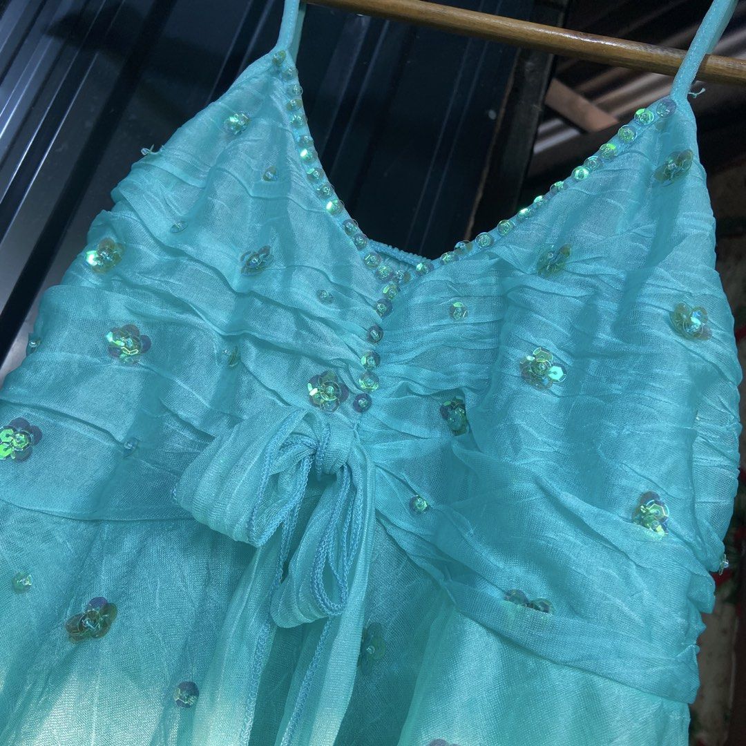 Turquoise Blue Sequin Embellished Reworked Top (Category: Dresses) located in Libungan. Submitted by whimsyypetal (Listing ID 1470550324, Image 2). Description: - Color: Bright turquoise blue - Design: Sleeveless with spaghetti straps and v-neckline - Details: Tiny sequin trim, bodice ruching, and cute tie-up waist bow - Skirt: Layered ruffles with scattered sequin floral accents - Fabric: Lightweight and sheer, perfect for parties and events.