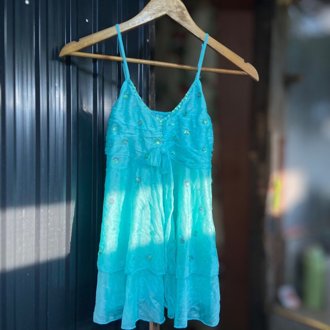 Turquoise Blue Sequin Embellished Reworked Top (Category: Dresses) located in Libungan. Submitted by whimsyypetal (Listing ID 1470550324, Image 1). Description: - Color: Bright turquoise blue - Design: Sleeveless with spaghetti straps and v-neckline - Details: Tiny sequin trim, bodice ruching, and cute tie-up waist bow - Skirt: Layered ruffles with scattered sequin floral accents - Fabric: Lightweight and sheer, perfect for parties and events.
