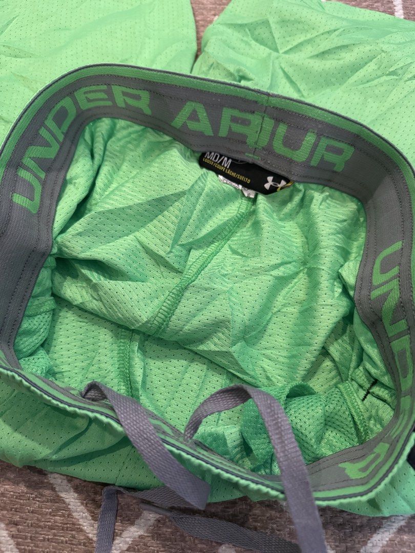 Under Armour Green Athletic Shorts Medium (Category: Shorts) located in Bulacan. Submitted by zyannechlo86360 (Listing ID 1470357297, Image 3). Description: - Brand: Under Armour - Color: Green with grey waistband and side stripes - Size: Medium - Features: Elastic waistband, adjustable drawstring, small logo on lower left leg - Material: Lightweight mesh - Ideal for: Workouts, running, and casual athletic wear 28-34 waist 19 length Excellent Loc